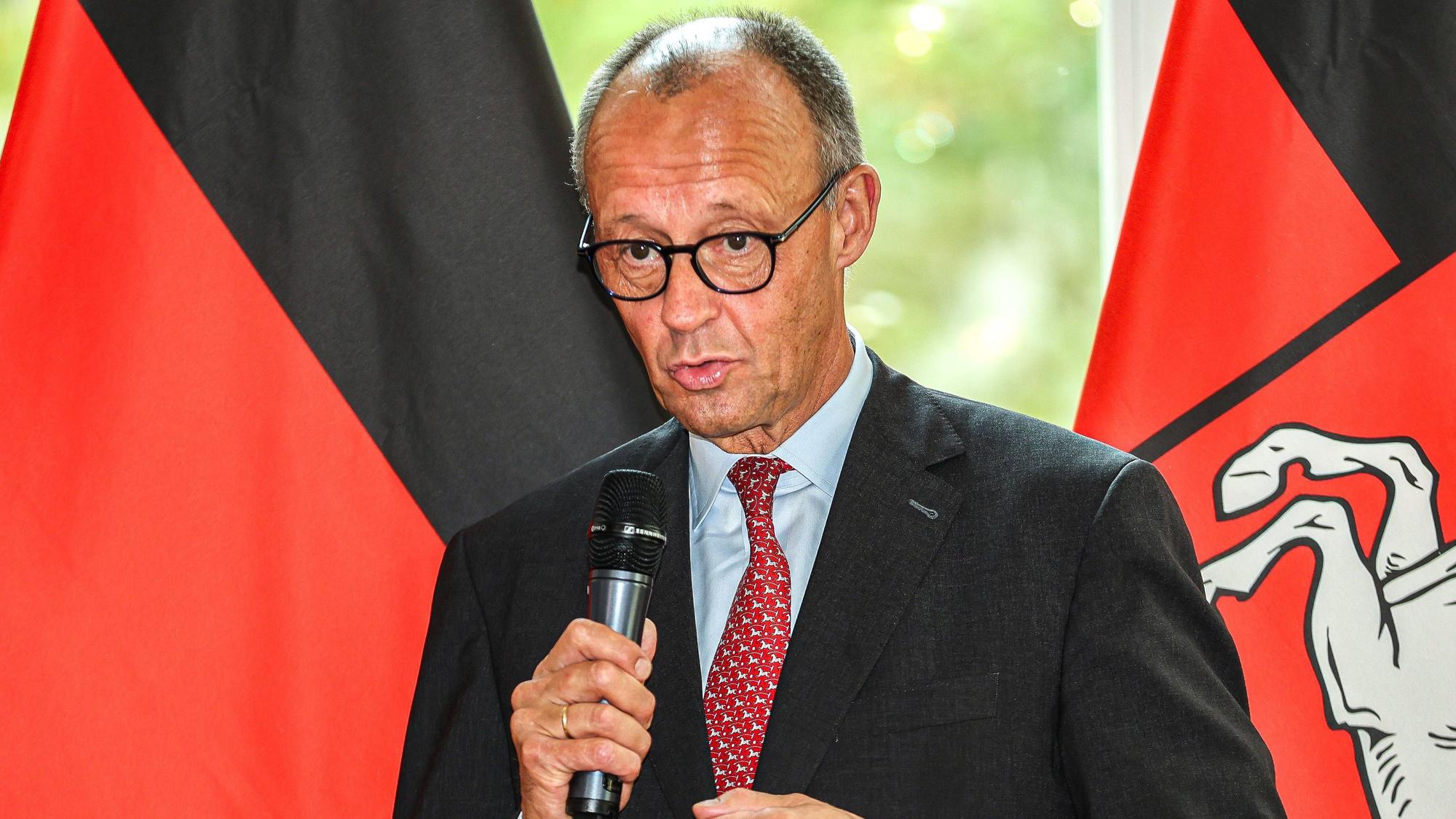 Bundeskanzler Friedrich Merz trägt eine Rote Krawatte mit weißen Pferdemotiven in Niedersachsen am 22. Juli.