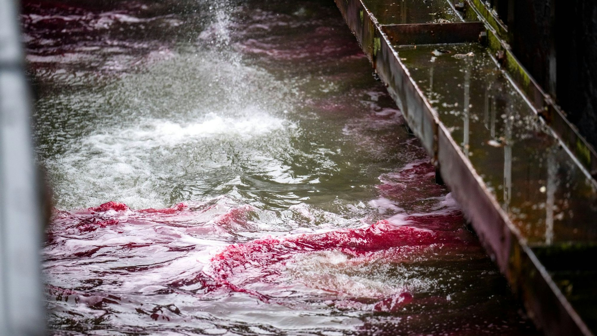 Ein roter Ölteppich bereitet sich auf dem Wasser aus.