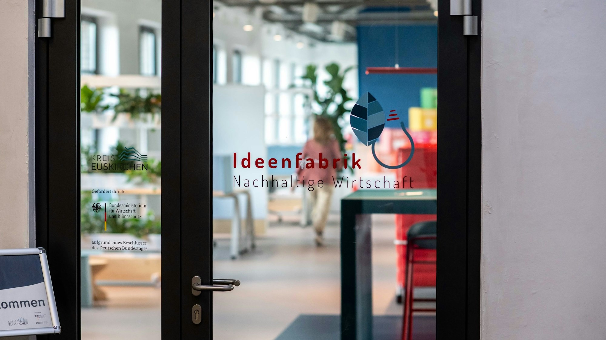 Auf einer Glastür ist die Aufschrift „Ideenfabrik Nachhaltige Wirtschaft“ aufgeklebt