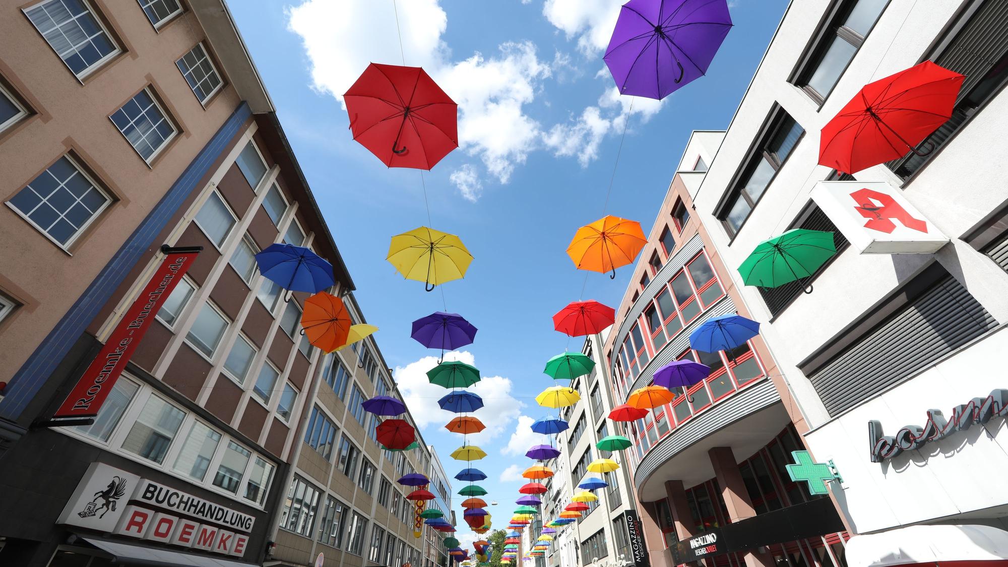 23.07.2025, Köln: Bunte Regenschirme hängen an der Apostelnstraße. In den Nächsten Tagen wird es viel regnen. Foto: Arton Krasniqi