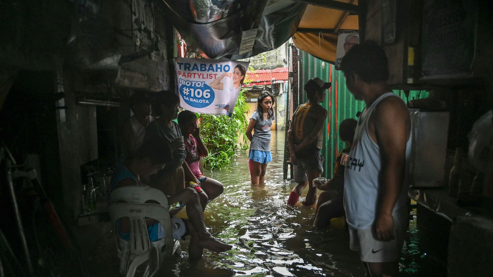 Menschen waten am 24. Juli 2025 durch ein überschwemmtes Gebiet in Malabon, Metro Manila. Die Philippinen schlossen am 24. Juli Schulen und sagten Flüge ab, als heftige Regenfälle, verursacht durch einen Taifun und einen separaten Tropensturm, die nördliche Insel Luzon des Landes heimsuchten.