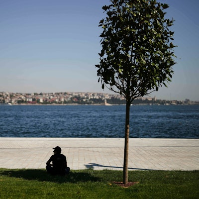 Ein Mann sucht an einem heißen Sommertag in Istanbul Schutz unter einem Baum.