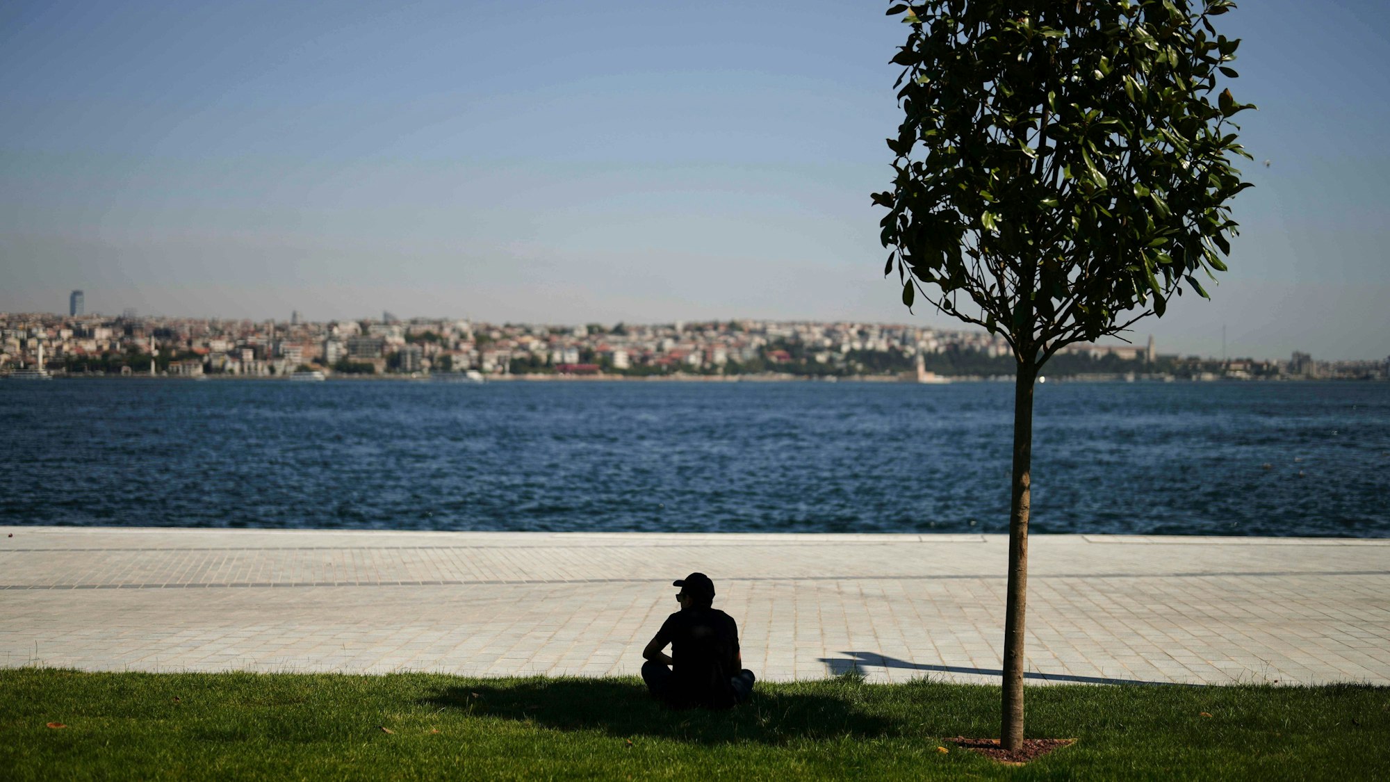 Ein Mann sucht an einem heißen Sommertag in Istanbul Schutz unter einem Baum.