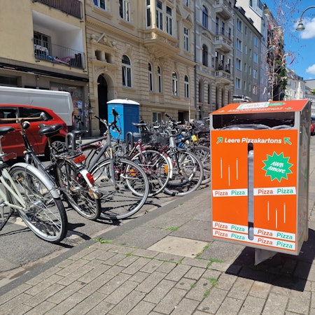 Im Belgischen Viertel steht ein neuer Mülleimer der Stadt für leere Pizzakartons.