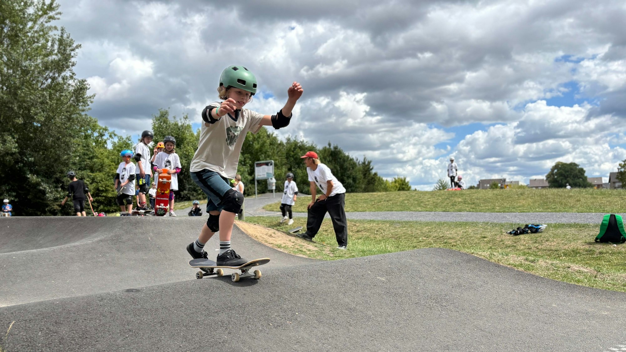 Ein Junge mit Helm und Schützern fährt auf einer hügeligen Strecke.