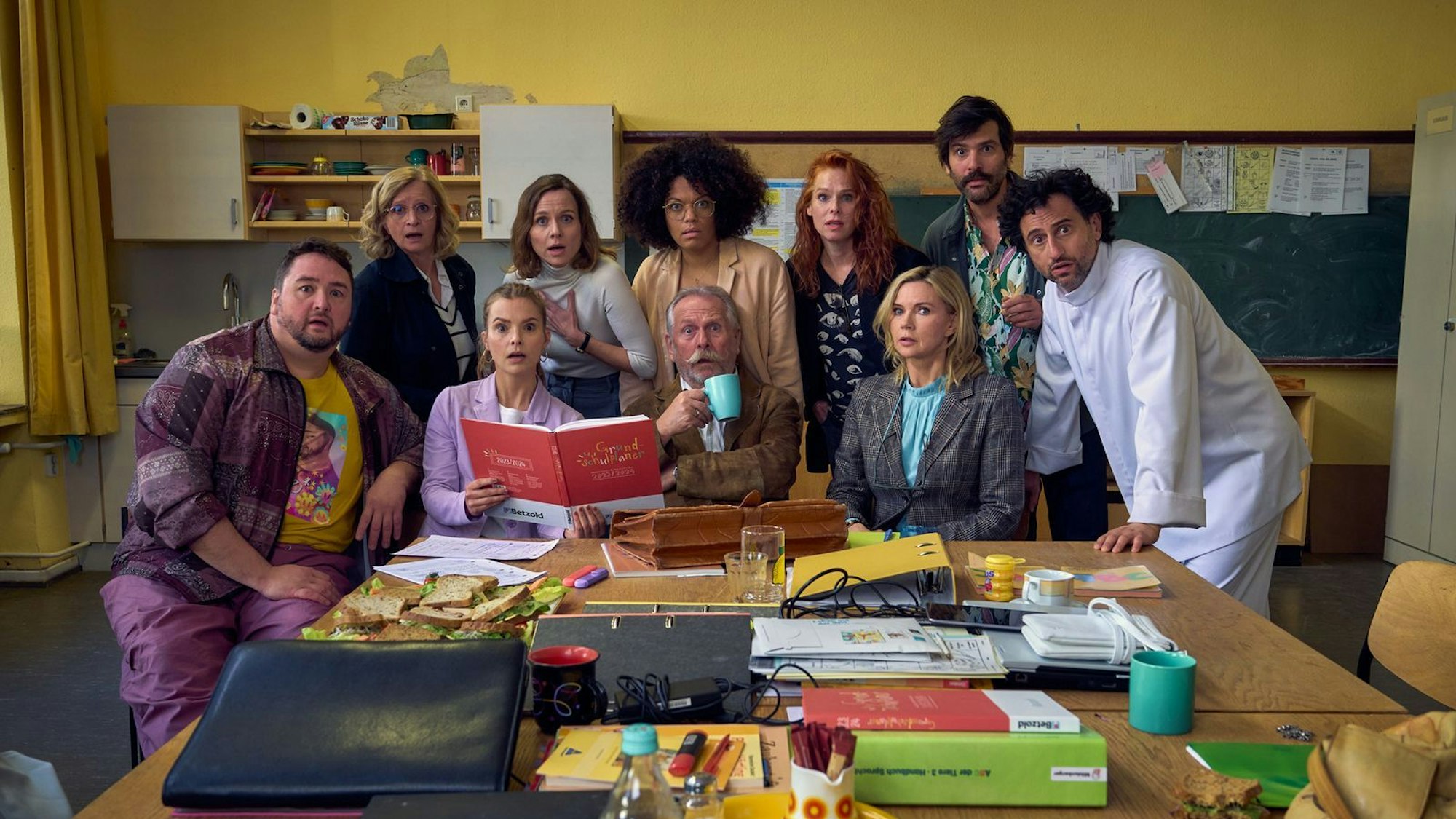 Die hoch gelobte Impro-Serie „Andere Eltern“ über eine Kita-Gründung geht einige Jahre später als Film und in der Grundschule weiter. Das Ensemble des ZDF-Films umfasst unerwartete Stars wie Veronica Ferres (dritte von rechts) als Direktorin oder Ex-Höhner-Sänger Henning Krautmacher (Mitte, vorn).