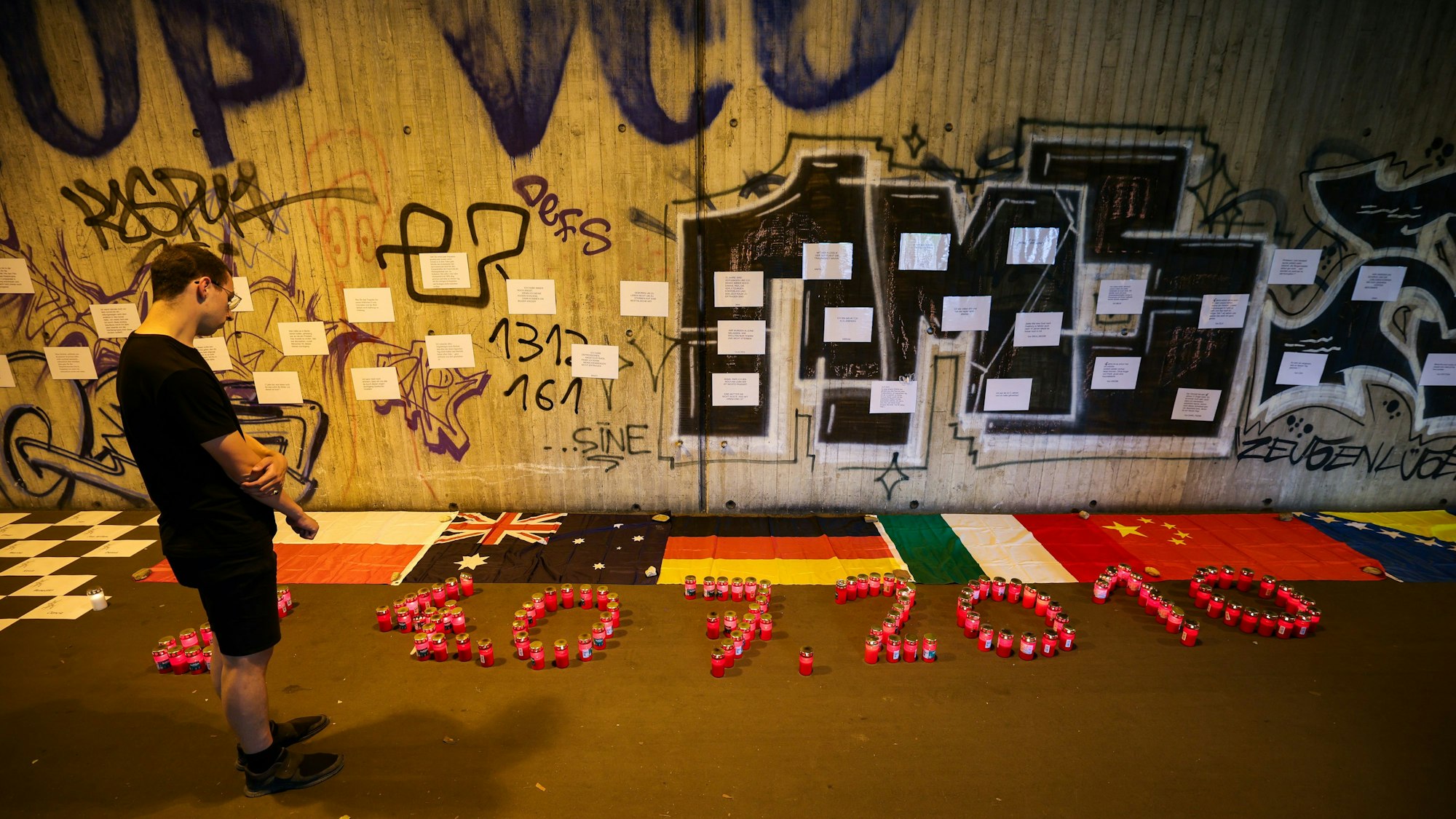 Ein Mann steht im Tunnel in der Nähe des Unglücksortes vor Kerzen, die das Datum 24.07.2010 zeigen. Zahlreiche Menschen haben mit einer Nacht der 1.000 Lichter an die Opfer der Loveparade-Katastrophe vor 15 Jahren erinnert. (Archivbild)