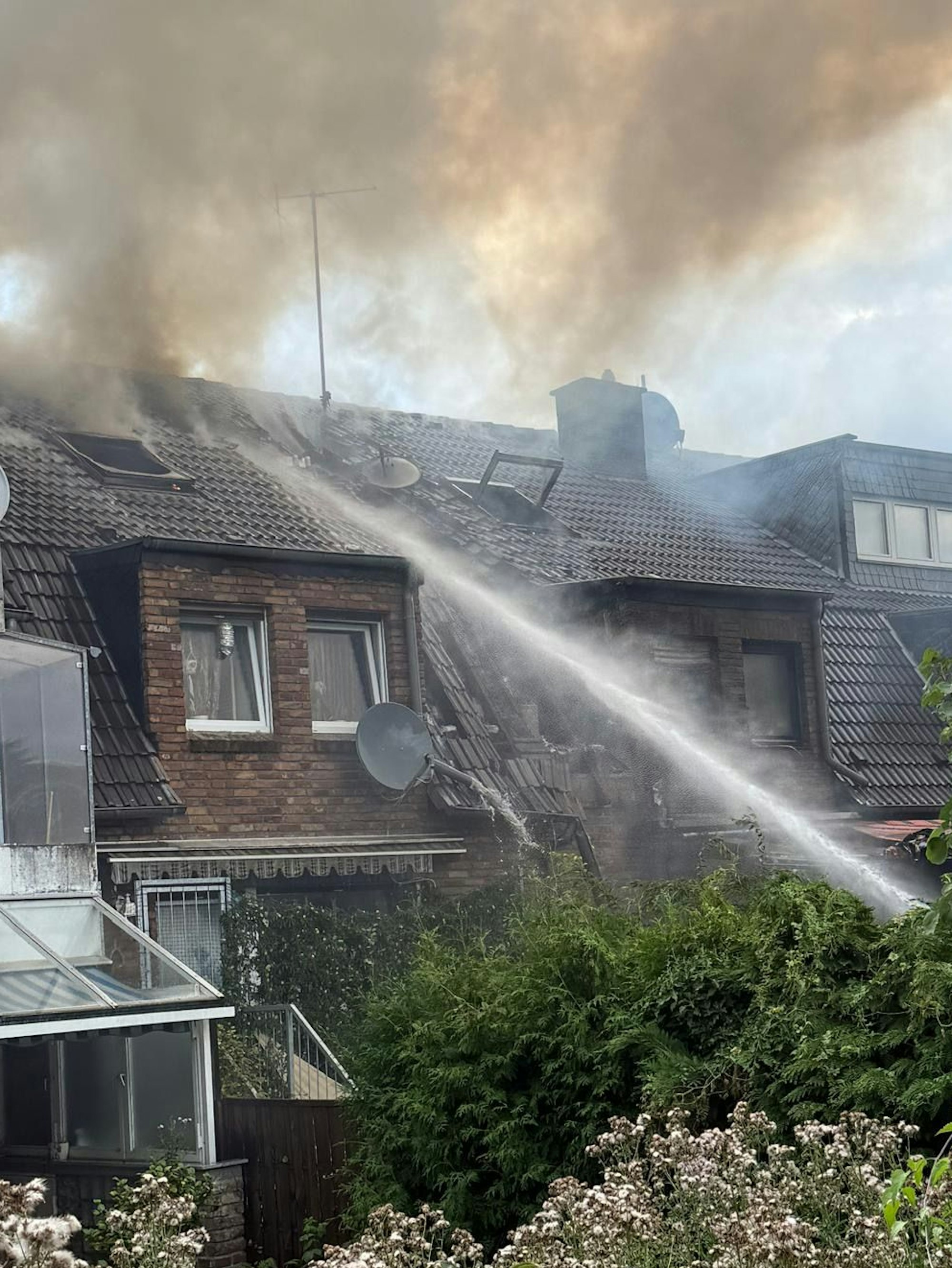 Das Bild zeigt Reihenhäuser mit qualmenden Dächern.