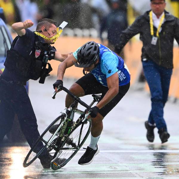 Ein Sicherheitsmann stößt einen Radfahrer im Ziel der Tour de France zu Boden.