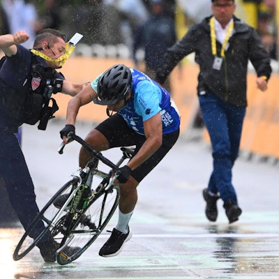 Ein Sicherheitsmann stößt einen Radfahrer im Ziel der Tour de France zu Boden.