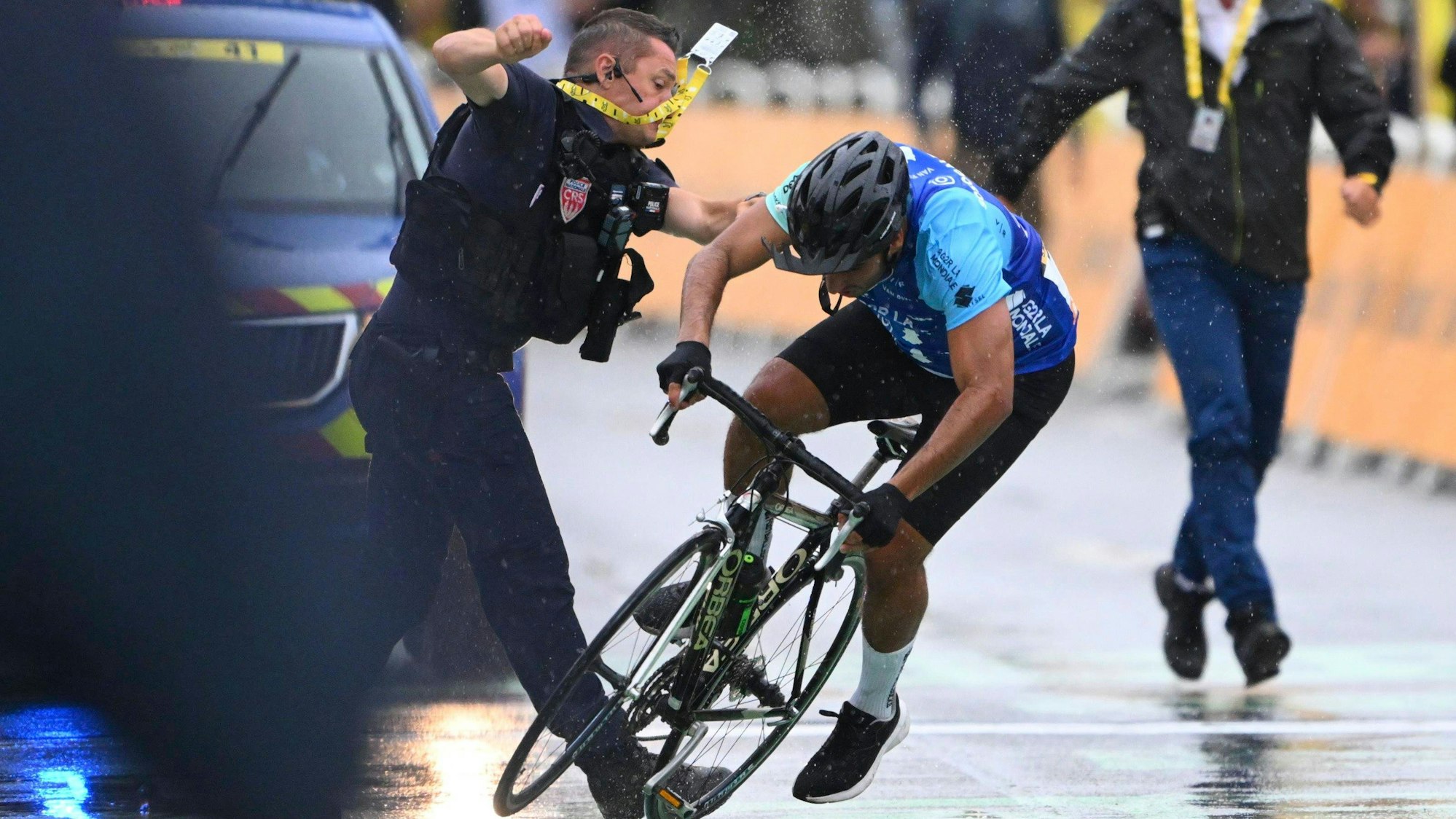 Ein Sicherheitsmann stößt einen Radfahrer im Ziel der Tour de France zu Boden.