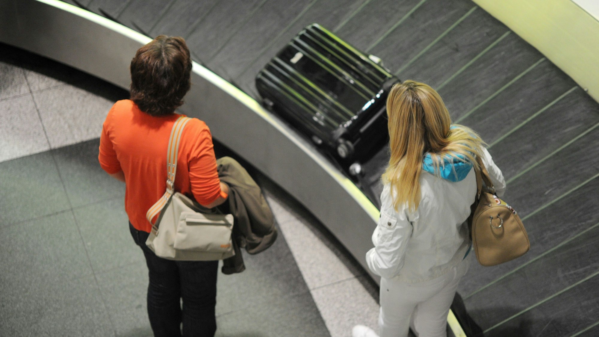 Zwei Frauen stehen an einem Gepäckband