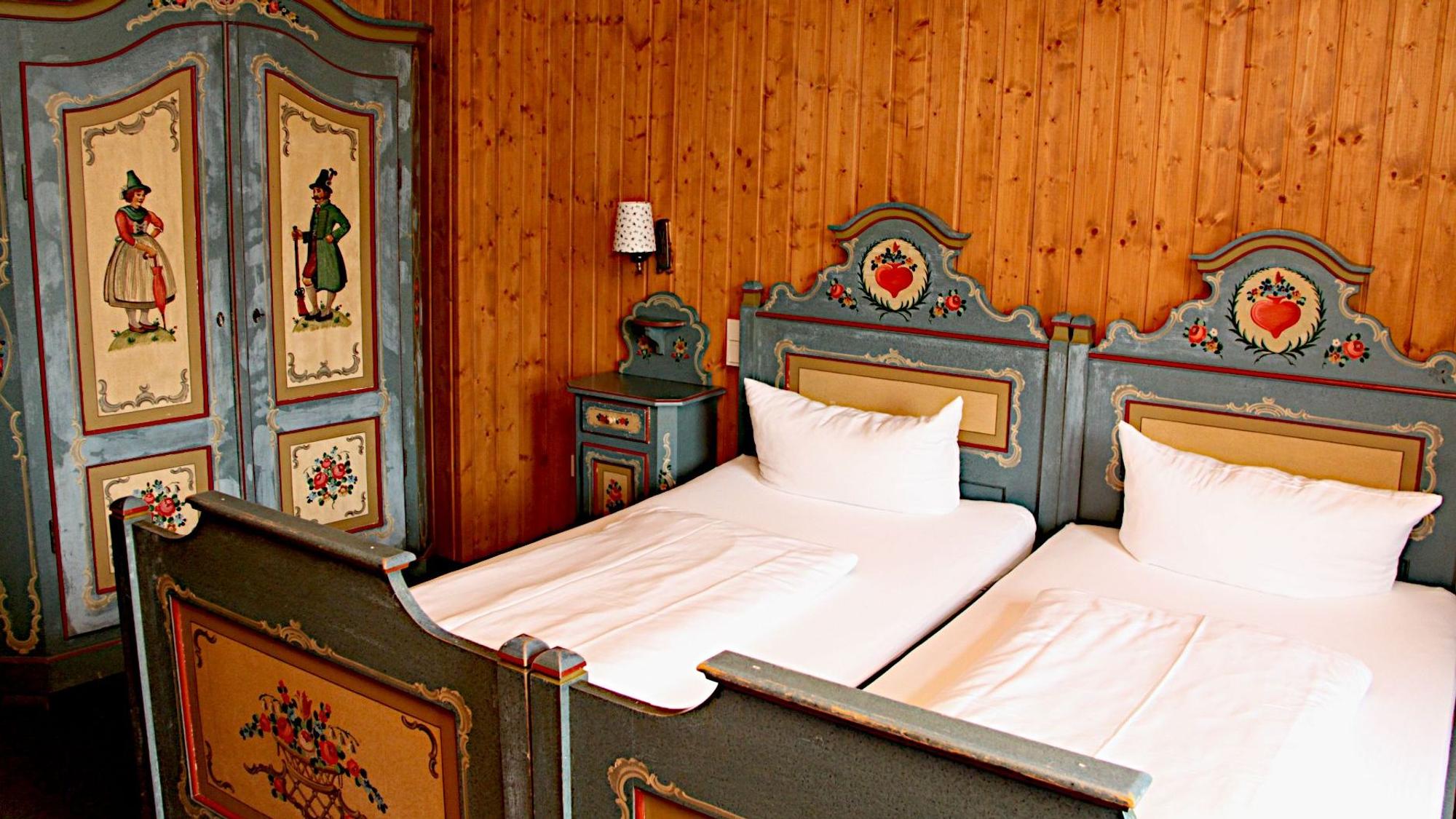 Das Zimmer ist dem aus der Krimiserie bekannten bayerischen Zimmer einer Pension nachempfunden, mit bemaltem Bett und Bauernschrank.