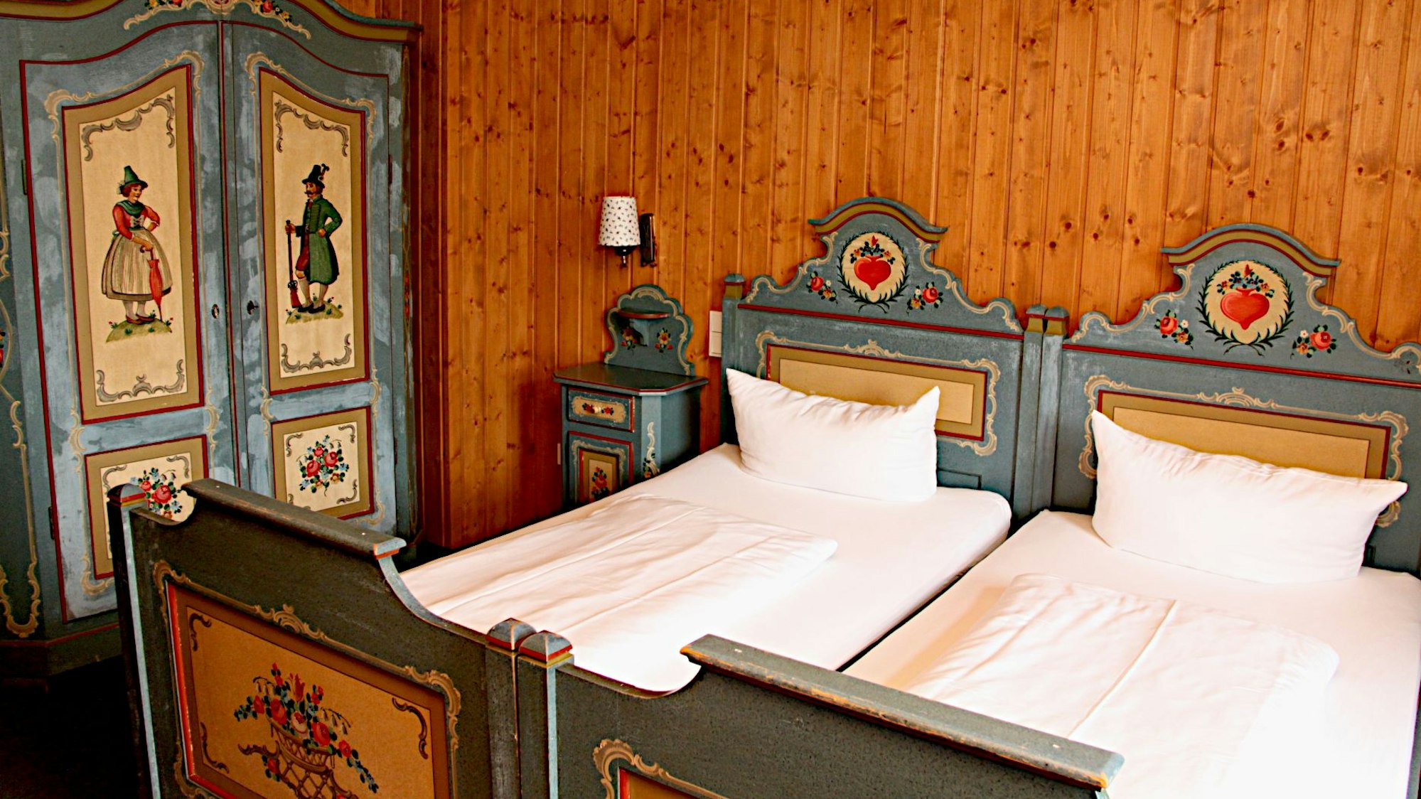 Das Zimmer ist dem aus der Krimiserie bekannten bayerischen Zimmer einer Pension nachempfunden, mit bemaltem Bett und Bauernschrank.