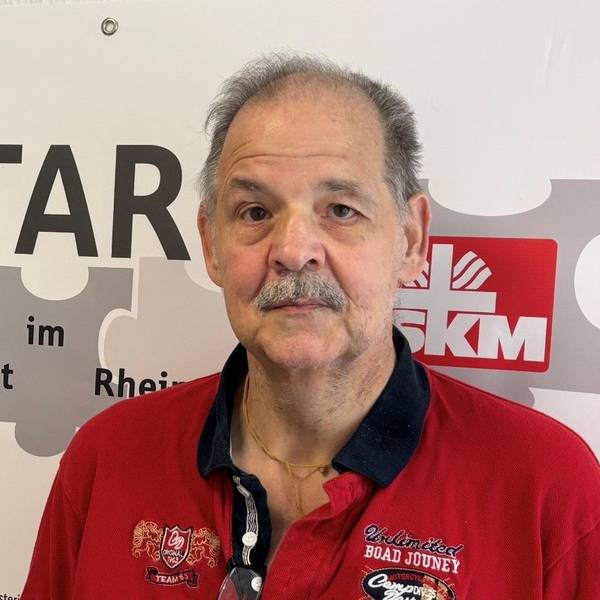 Auf dem Bild ist das Portrait eines Mannes zu sehen, er trägt ein rotes Poloshirt.