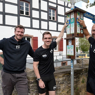 Den Eifelsteig fest im Blick haben Henrik Züll (von links), Sebastian Nelles und Andreas Winkler (rechts), die neben einem Wanderwegweiser stehen.