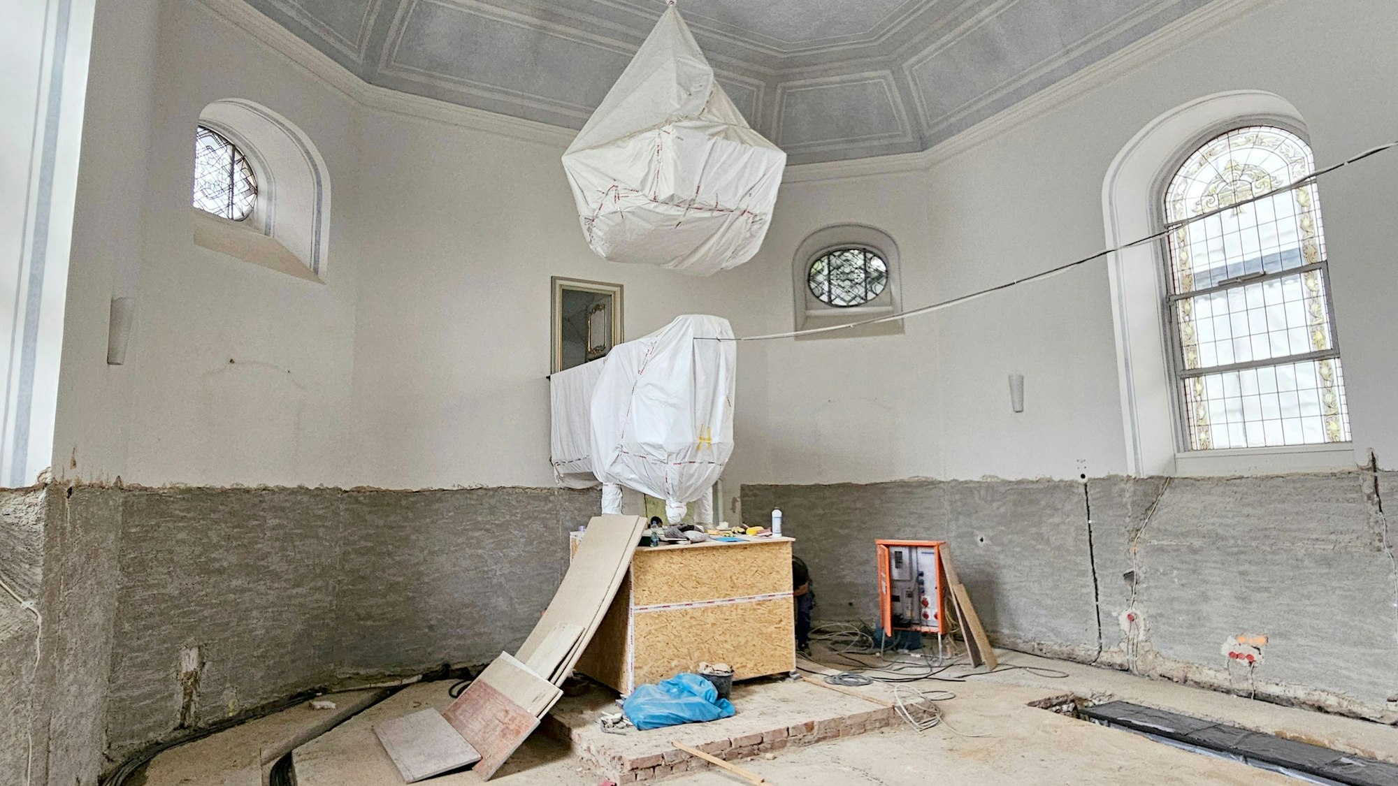 Der Wandputz wurde bis zu den Kirchenfenstern abgeschlagen. Der Boden ist an mehreren Stellen geöffnet. Leitungen sind zu sehen.