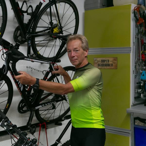 Andreas Großpietsch steht vor seinem Fahrrad, welches an der Wand hängt.