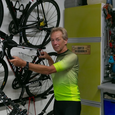 Andreas Großpietsch steht vor seinem Fahrrad, welches an der Wand hängt.