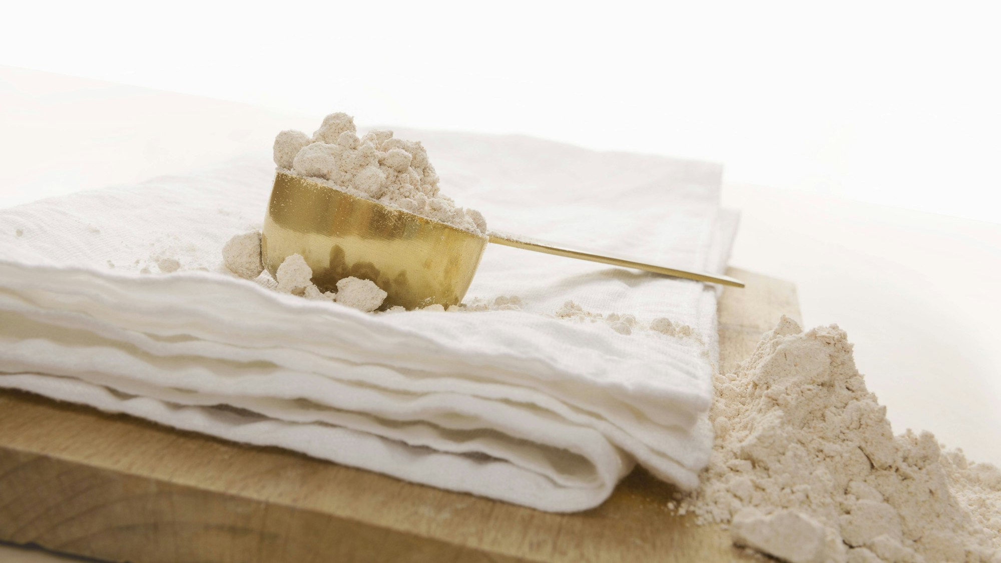 Vollkornmehl und Schaufel auf hölzernem Küchenbrett auf weißem Hintergrund.