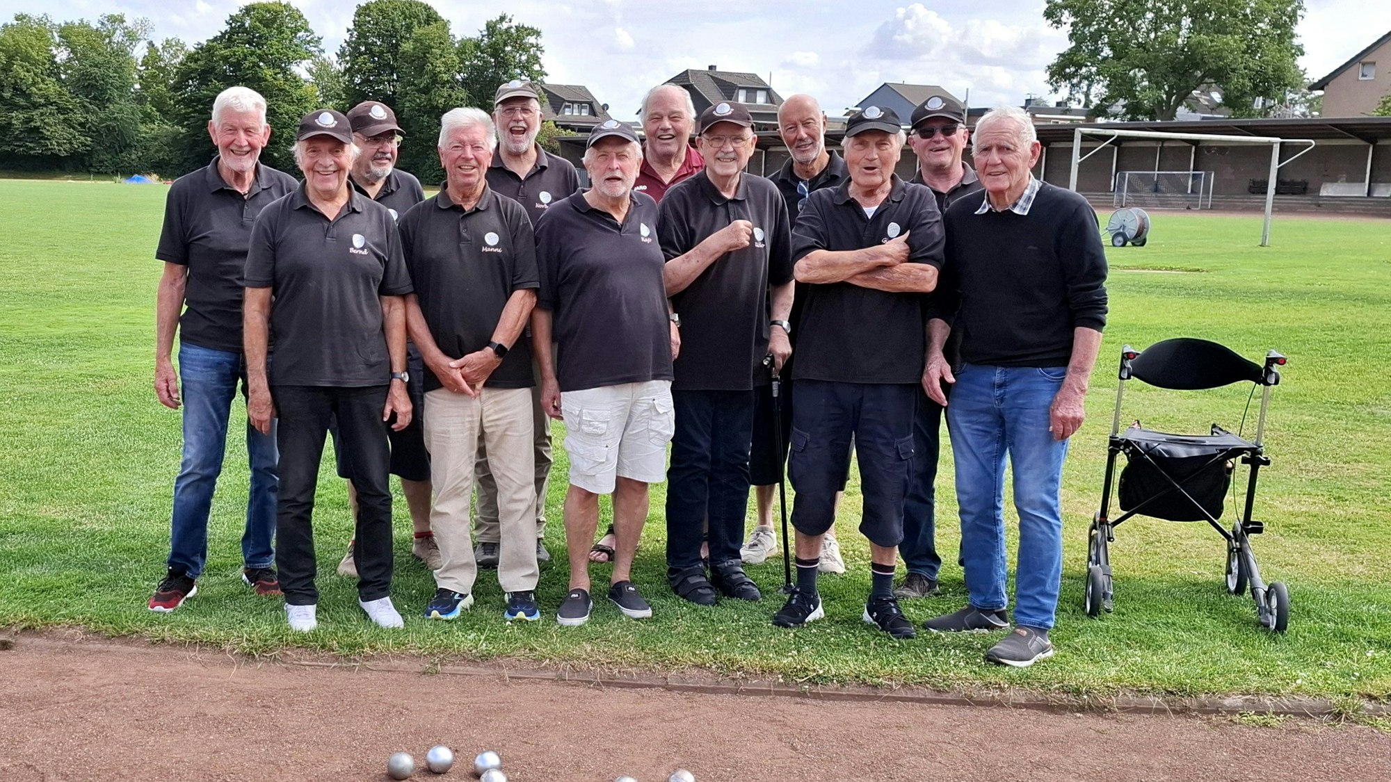 Auf dem Gruppenbild sind die Herren des Vereins zu sehen. Auf der Bahn vor ihnen haben sie Boulekugeln gelegt, die die Zahl 20 formen.