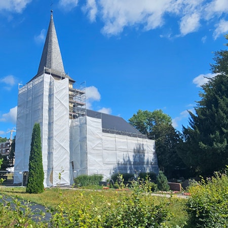 Turm und eine Seite der evangelischen Kirche in Schleiden sind mit Planen verhüllt.