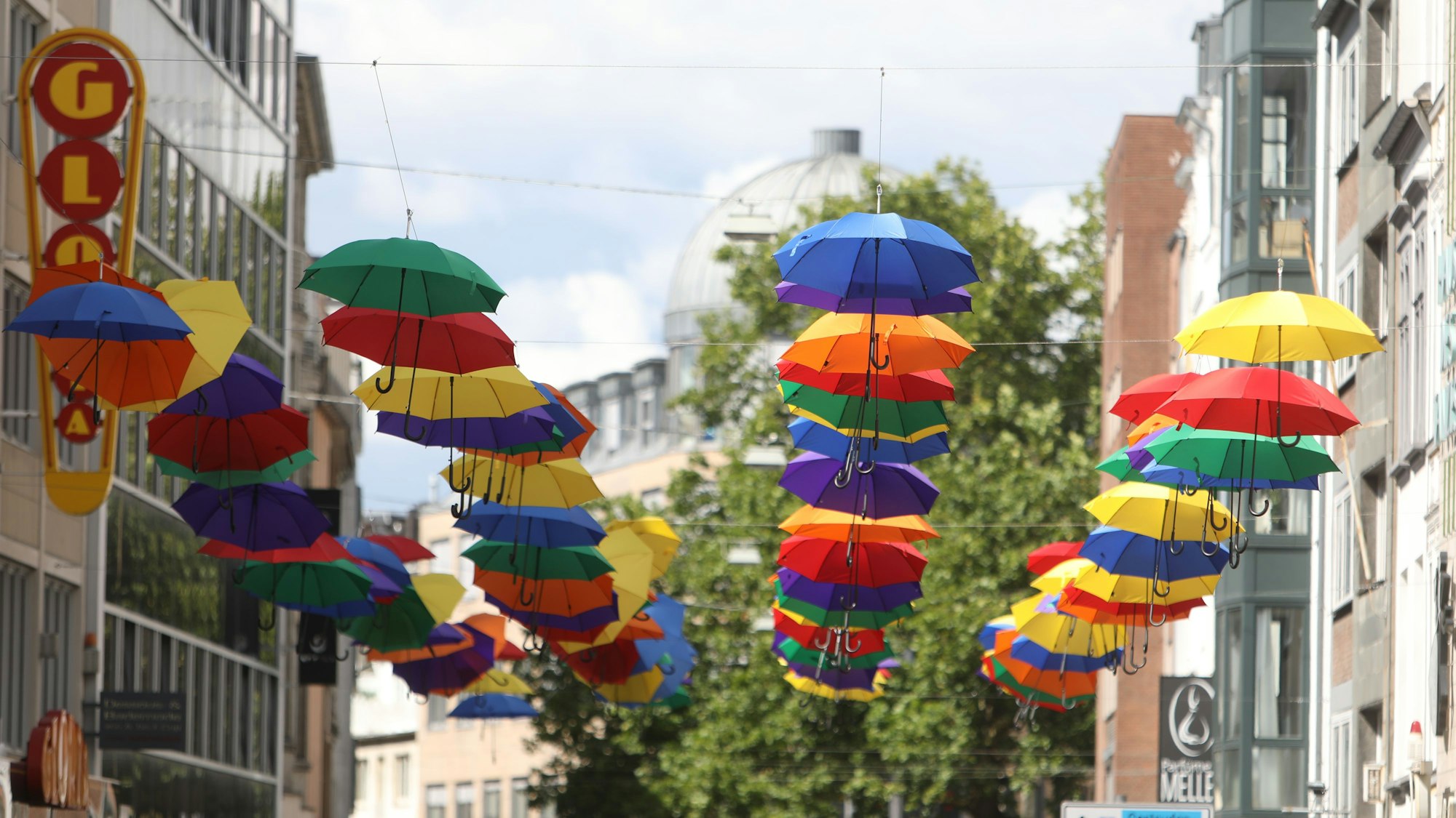 23.07.2025, Köln: Bunte Regenschirme hängen an der Apostelnstraße. In den Nächsten Tagen wird es viel regnen. Foto: Arton Krasniqi