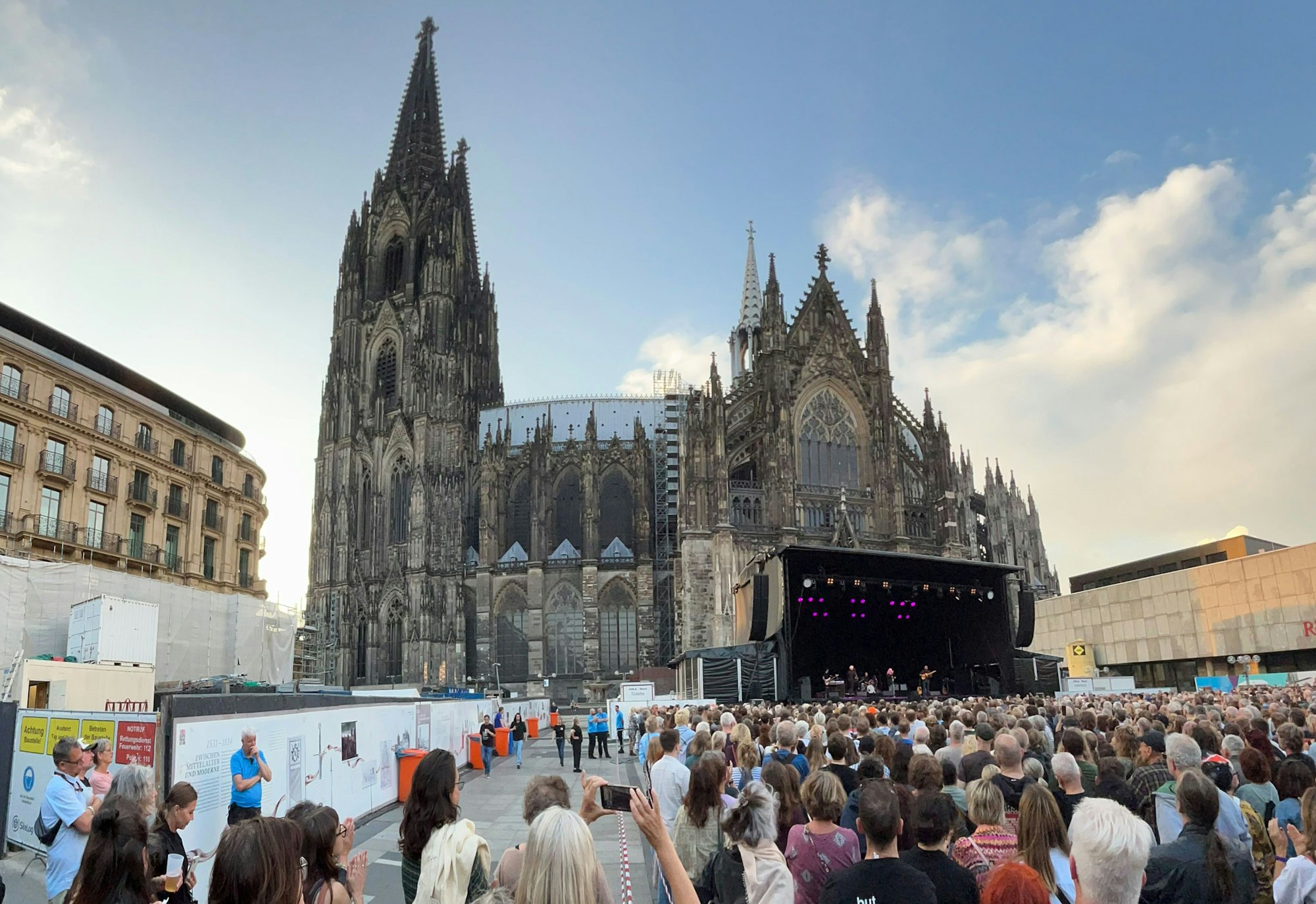 Vor der Südfassade des Doms stehen die Besucher des Patti-Smith-Konzerts am 25. Juli 2025.