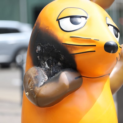 Mit einem großen Brandfleck steht die Maus vor dem WDR-Gebäude.