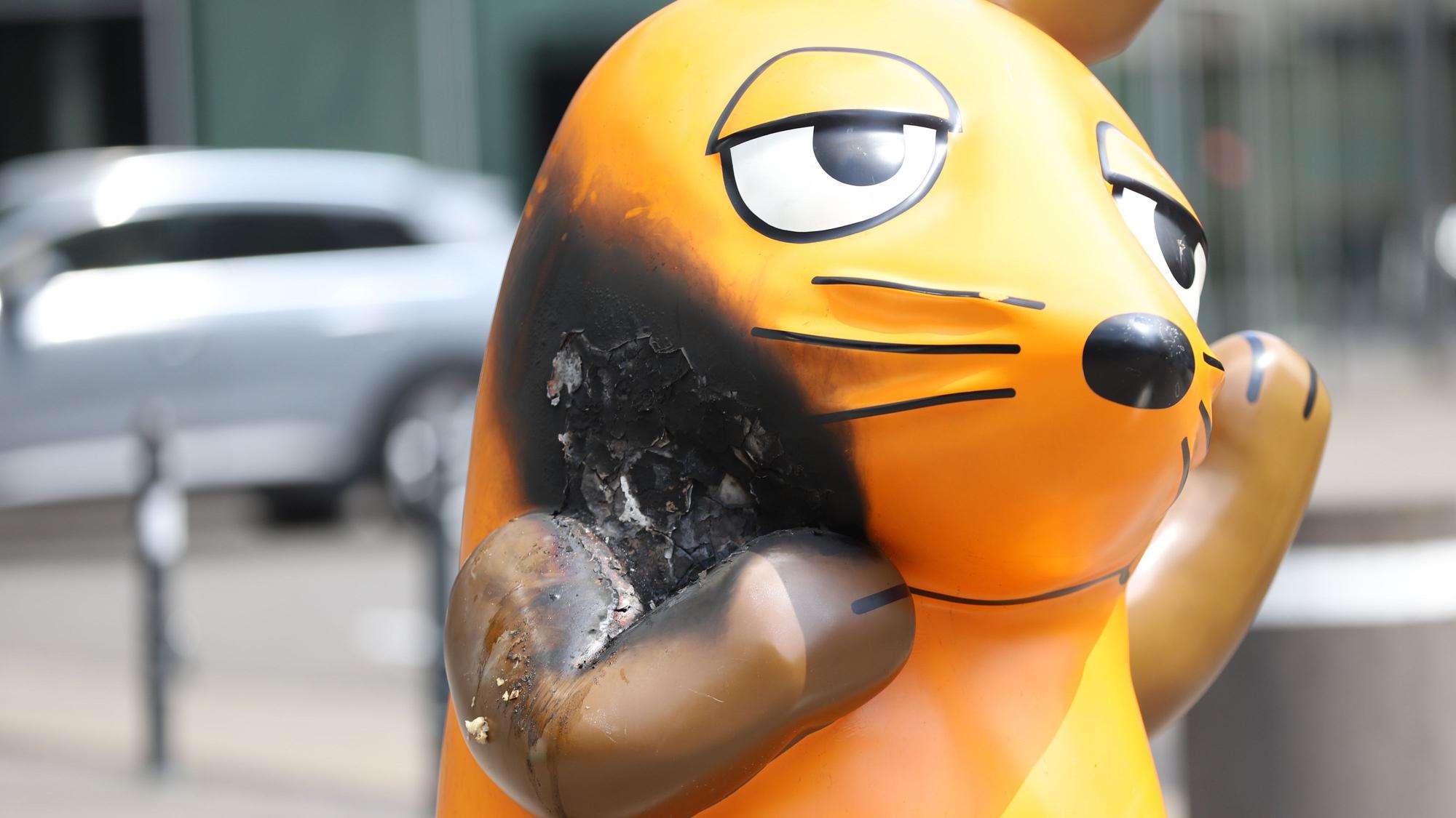 Mit einem großen Brandfleck steht die Maus vor dem WDR-Gebäude.