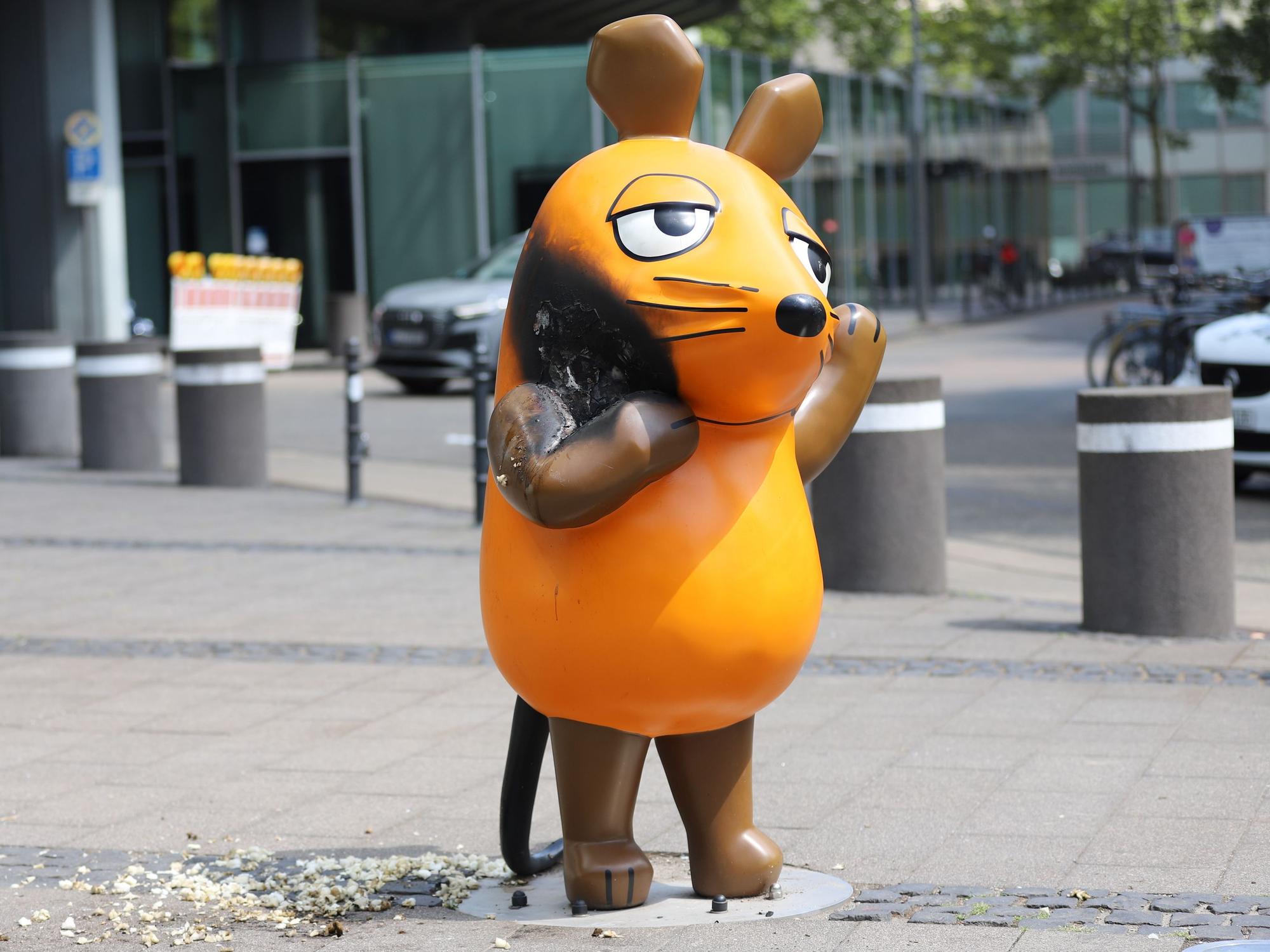 Mit einem großen Brandfleck steht die Maus vor dem WDR-Gebäude. Unbekannte hatten die Figur – ein beliebtes Fotomotiv in der Innenstadt – in der Nacht in Brand gesetzt.