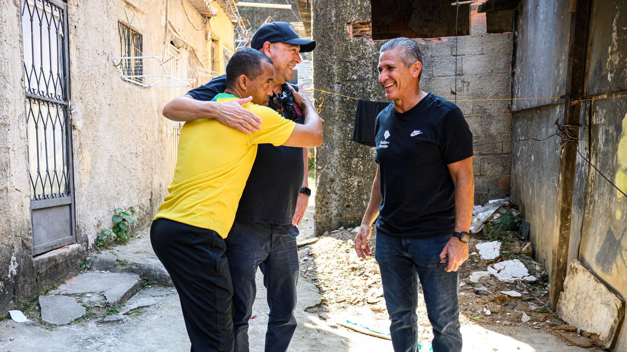 Favela-Einwohner Mineiro (l.) umarmt Bayer-04-Chef Fernando Carro. Daneben Jorginho.