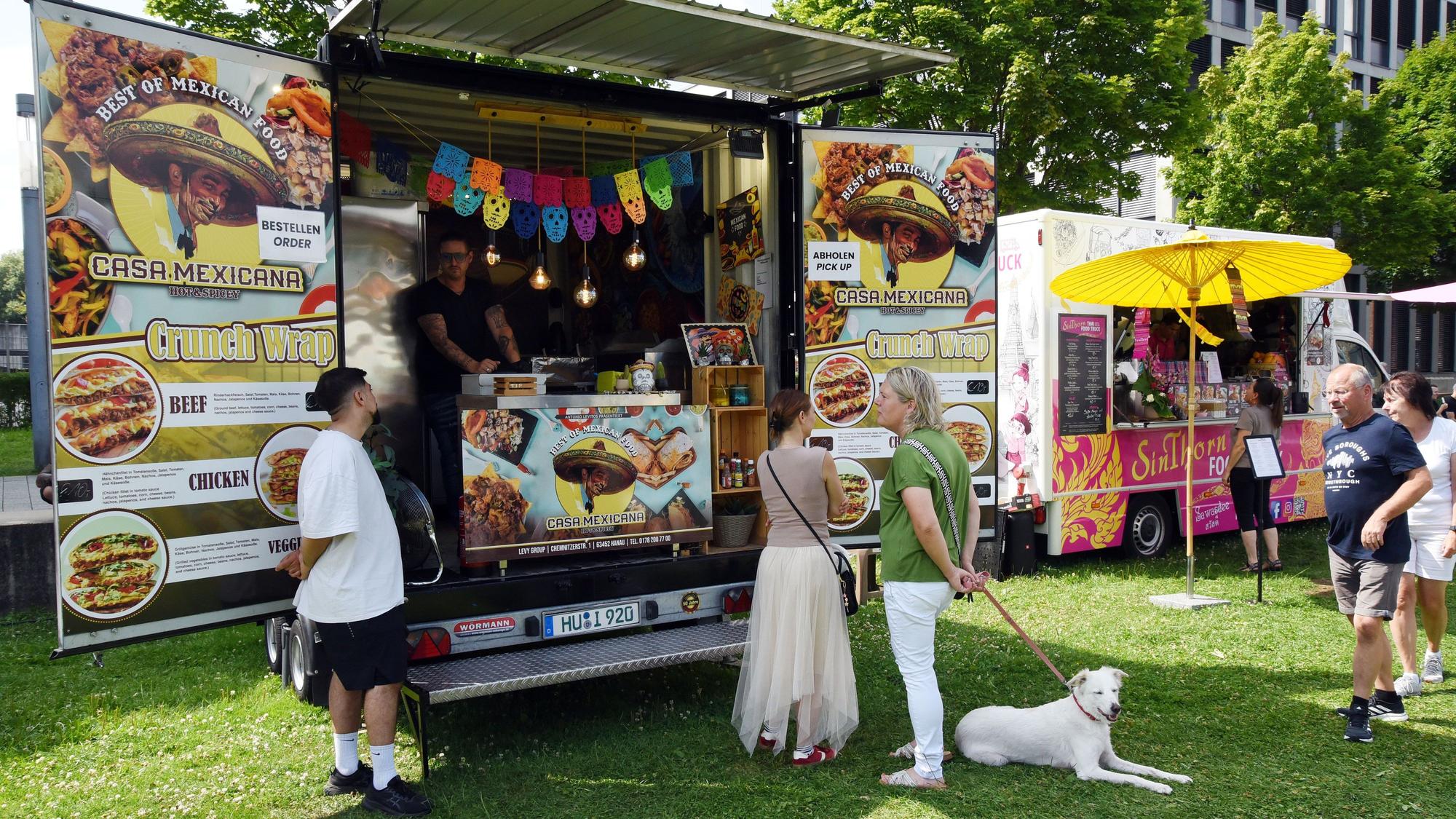 Ein paar Leute mit einem weißen Hund stehen vor dem mexikanischen Foodtruck "Casa Mexicana".