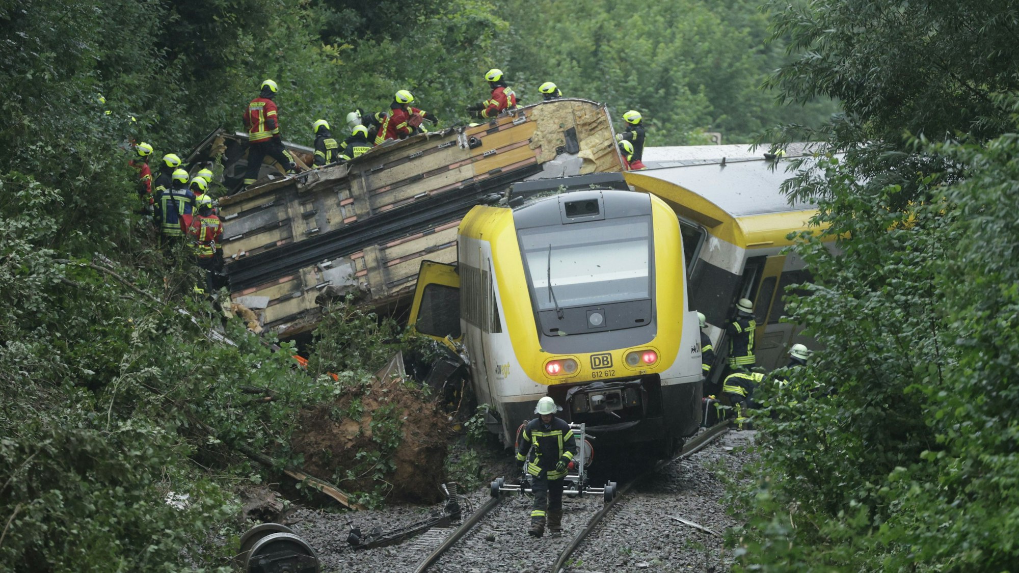 Die Waggons eines Zuges liegen quer hintereinander. Auf einem Waggon sind zahlreiche Rettungskräfte zu sehen.