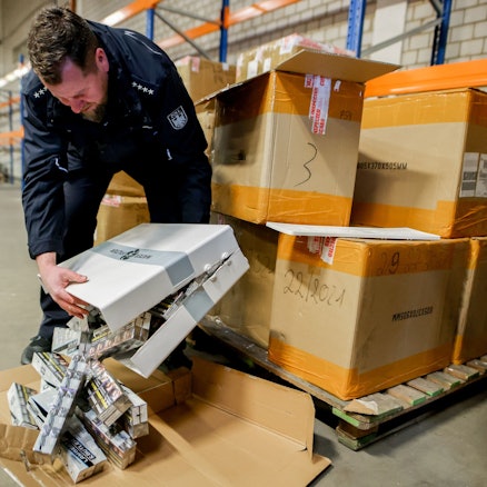 Zollsprecher Jens Ahland öffnet ein Paket mit sichergestellten Schmuggel-Zigaretten. (Archivbild)