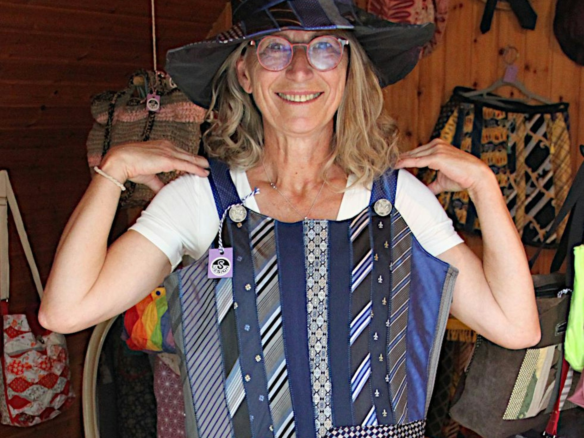 Eine Künstlerin präsentiert ein aus Krawatten genähtes Kleid und den dazu passenden Hut.
