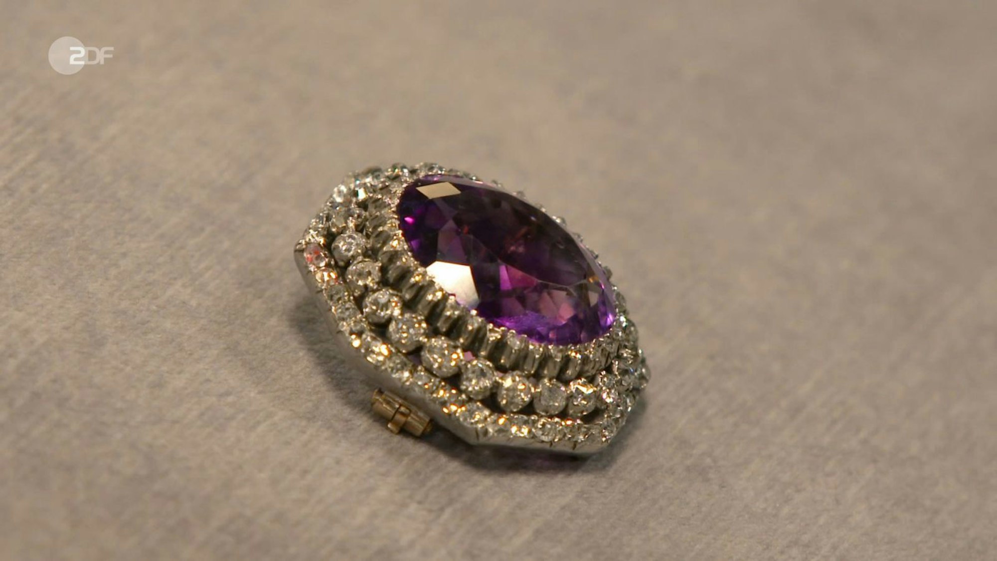 Eine Silber-Brosche mit 585er Gold, und einem Amethyst, eingerahmt von Diamanten: Für dieses besondere Schmuckstück erhoffte sich Ulrike 600 Euro. Wendela Horz taxierte auf bis zu 2.300. Exakt den Maximalschätzpreis bezahlte Elke Velten. (Bild: ZDF)