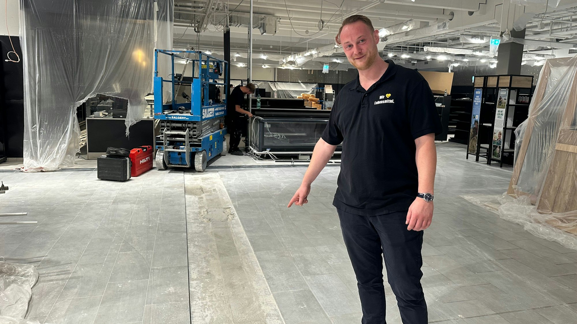 Severin Hemmersbach zeigt auf die Stelle, auf der bisher eine Wand stand, die den Überblick und die Laufwege im Laden behinderte.