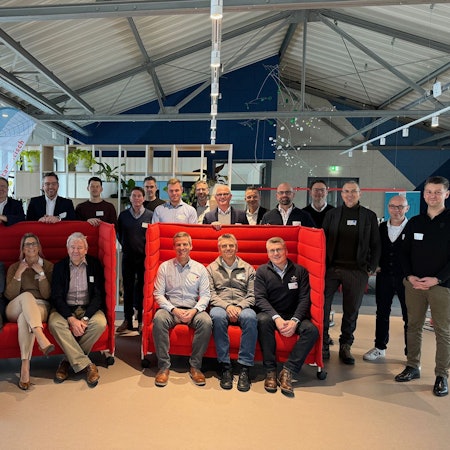 Gruppenfoto des Vorstands und der Führungskräfte der KSK Euskirchen. Sechs Leute sitzen auf zwei roten Sitzbänken, die übrigen haben sich dahinter gruppiert.