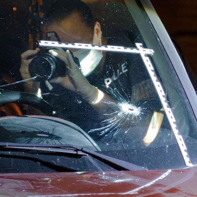 Schüsse in Holweide: Ein Polizeibeamter fotografiert Einschusslöcher in einer Windschutzscheibe.