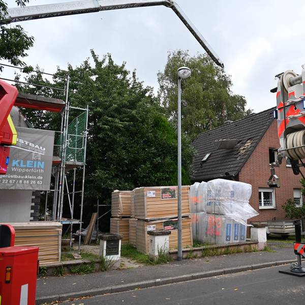 Der Ausleger eines Krans ragt in die Höhe, daran hängt ein Behälter.