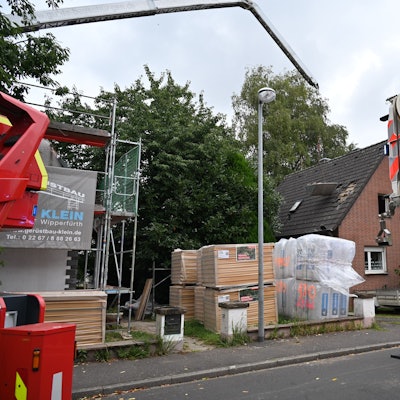 Der Ausleger eines Krans ragt in die Höhe, daran hängt ein Behälter.