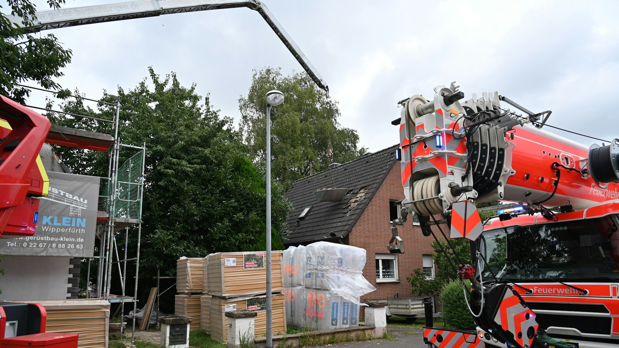 Der Ausleger eines Krans ragt in die Höhe, daran hängt ein Behälter.