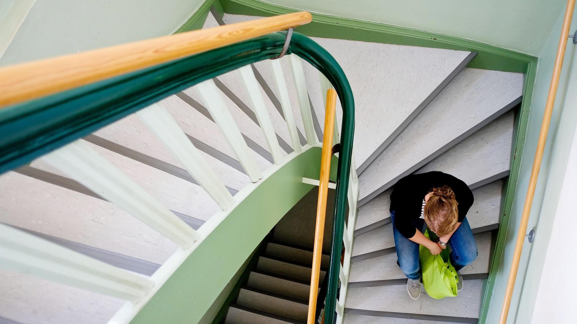 Eine junge Frau sitzt allein auf einer Treppe in Nienburg.