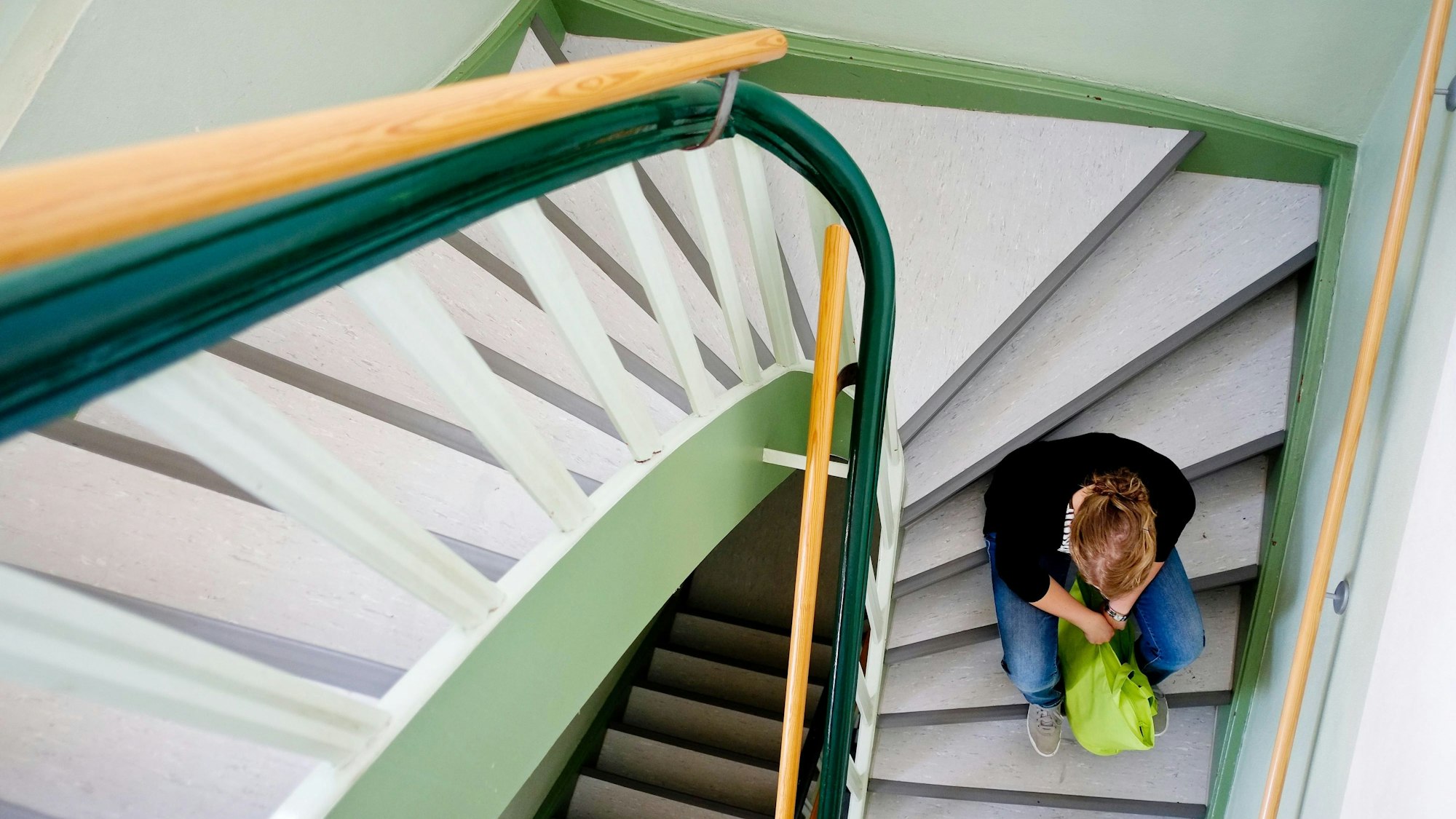 Eine junge Frau sitzt allein auf einer Treppe in Nienburg.