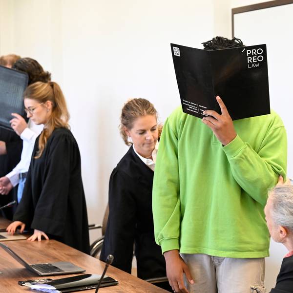 Die drei Angeklagten warten mit ihren Anwälten auf den Beginn des Prozesses im Landgericht.