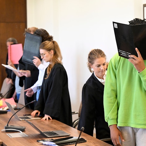Die drei Angeklagten warten mit ihren Anwälten auf den Beginn des Prozesses im Landgericht.