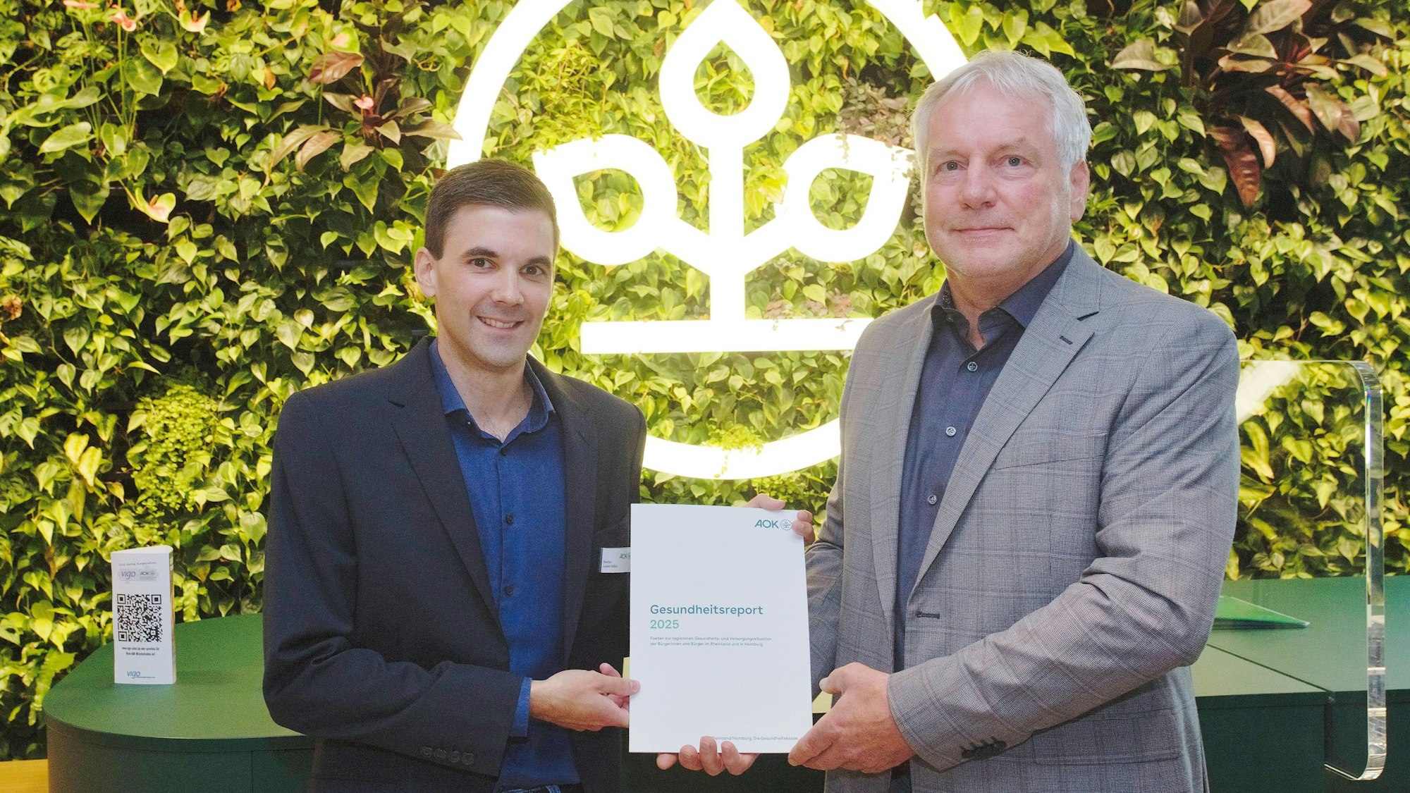 Zwei Männer halten eine Broschüre ins Bild.