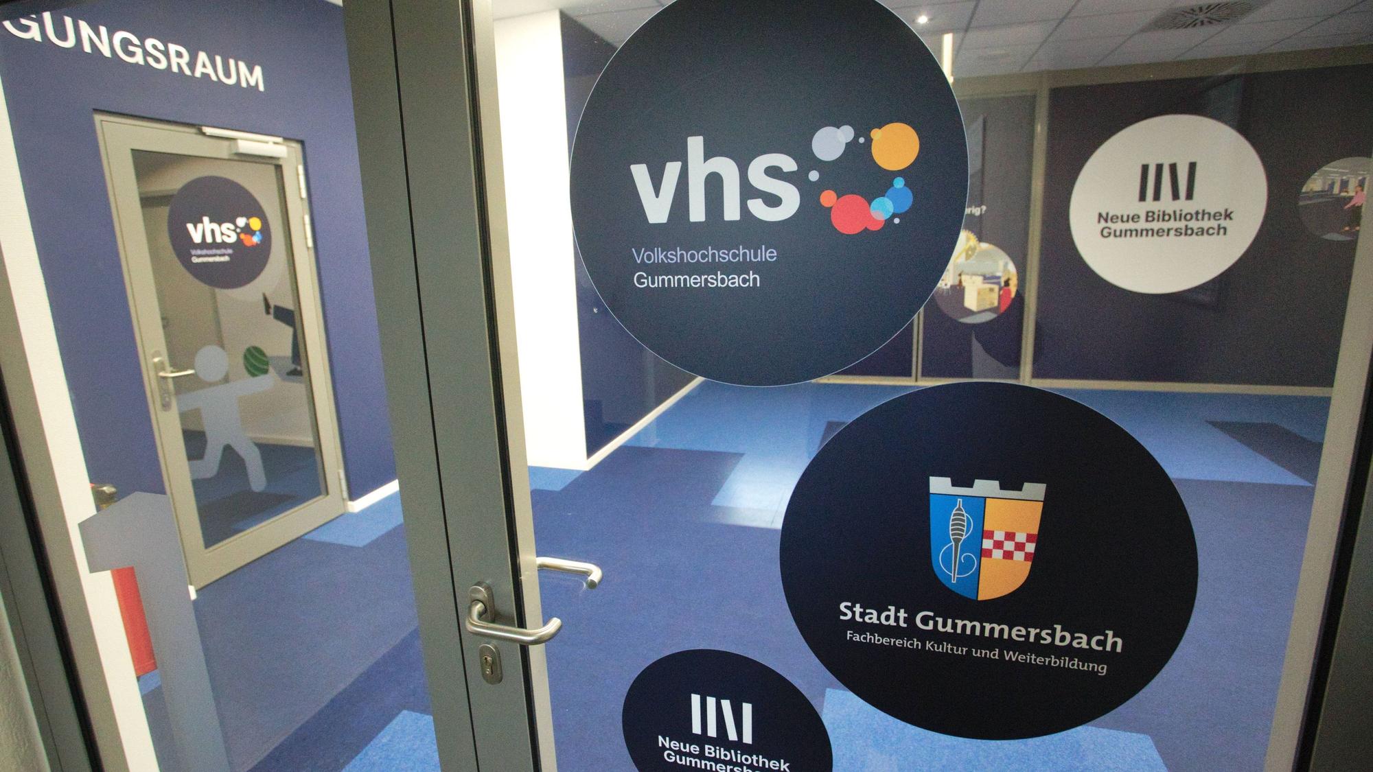 Eine Glastür mit mehreren Aufkleber der Volkshochschule, sowie der Stadt Gummersbach.