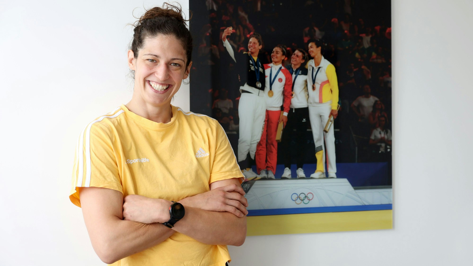 Miriam Butkereit steht vor einem Bild, das sie bei der Siegerehrung der Olympischen Spiele in Paris zeigt.